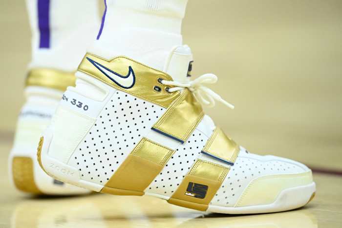 View of the white and gold Nike LeBron '20-5-5' shoes.